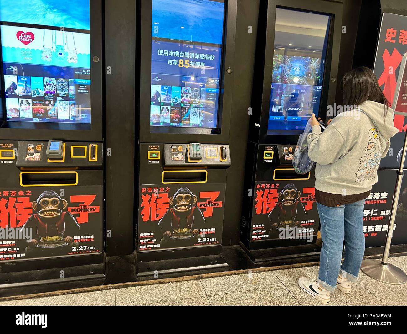 Taipei, Taiwan, Taipei, Taiwan, ragazzina taiwanese che compra biglietti per il cinema e paga al distributore automatico in un multiplex locale, adolescente che pensa - Immagine stock catturata con smartphone
