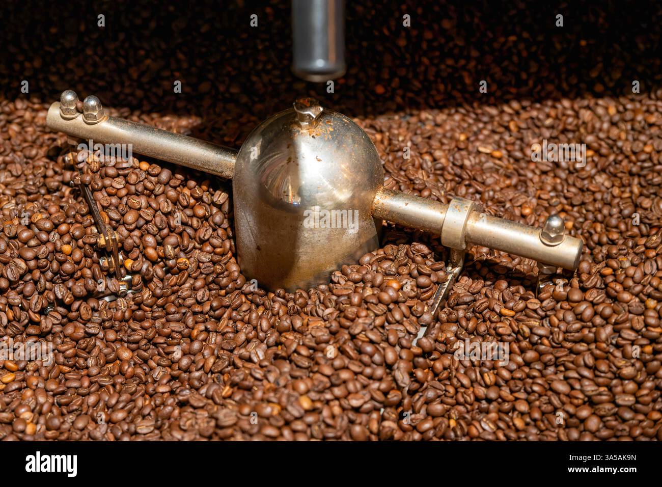 Giusto Gehandelter Kaffee. Blick auf die laufende Umrührmechanik im Kühlsieb einer Trommelröstmaschine mit Kaffeebohnen. Bonn Nordrhein-Westfalen Deutschland *** caffè equo e solidale Vista del meccanismo di agitazione in funzione nel crivello di raffreddamento di una torrefazione a tamburo con chicchi di caffè Bonn Renania settentrionale-Vestfalia Germania Foto Stock