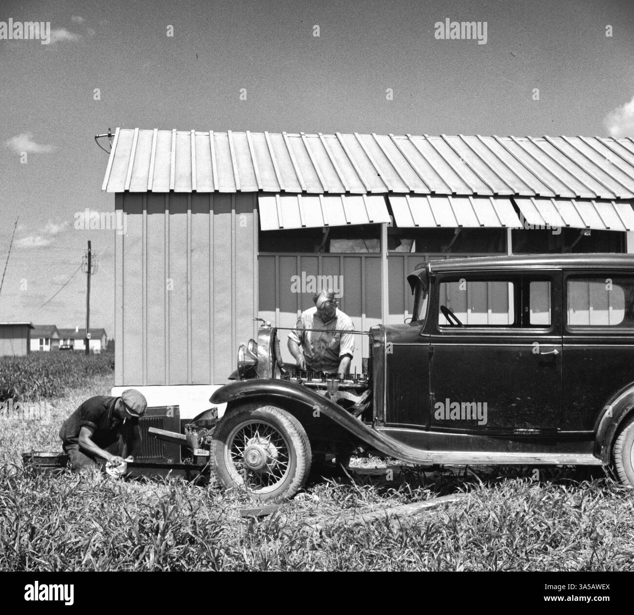 Membro del campo che ripara la sua auto fuori dal suo rifugio. Campo di lavoro migratorio di Osceola. Belle Glade, Florida, 1940 Foto Stock