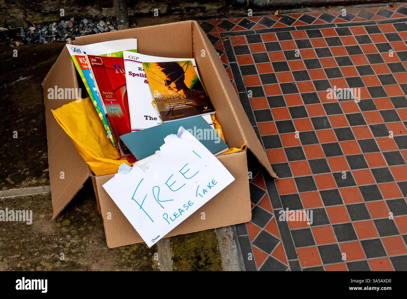 Una scatola di guide di revisione degli esami GCSE rimaste sulla pavimentazione per un riutilizzo gratuito. Inghilterra, Regno Unito Foto Stock