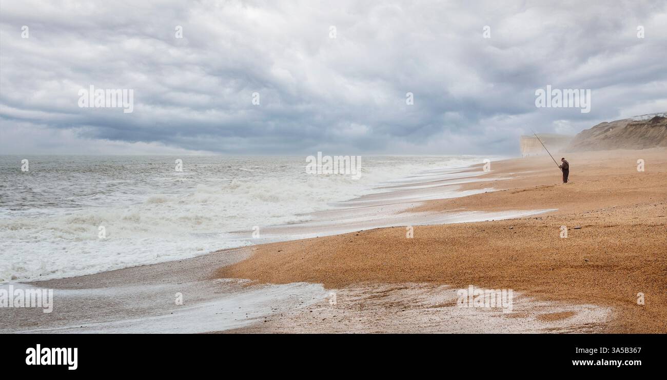 Pescatore solitario che pesca al largo della spiaggia a Burton Bradstock, Dortset, Regno Unito, l'11 aprile 2013 Foto Stock
