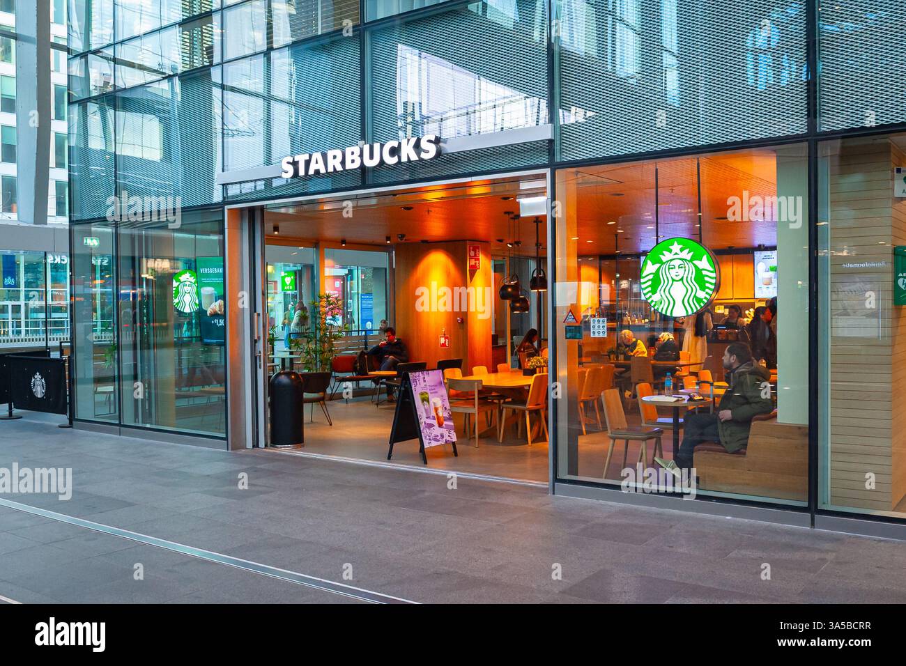 Starbucks Cafe con i clienti la mattina presto alla stazione centrale dell'Aia, nei Paesi Bassi Foto Stock