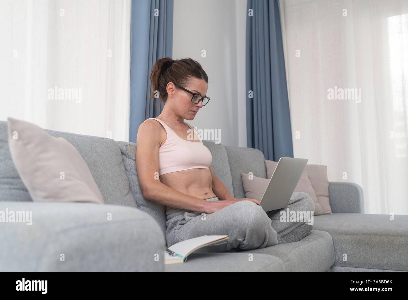 donna seduta sul divano che lavora sul suo computer portatile a casa Foto Stock