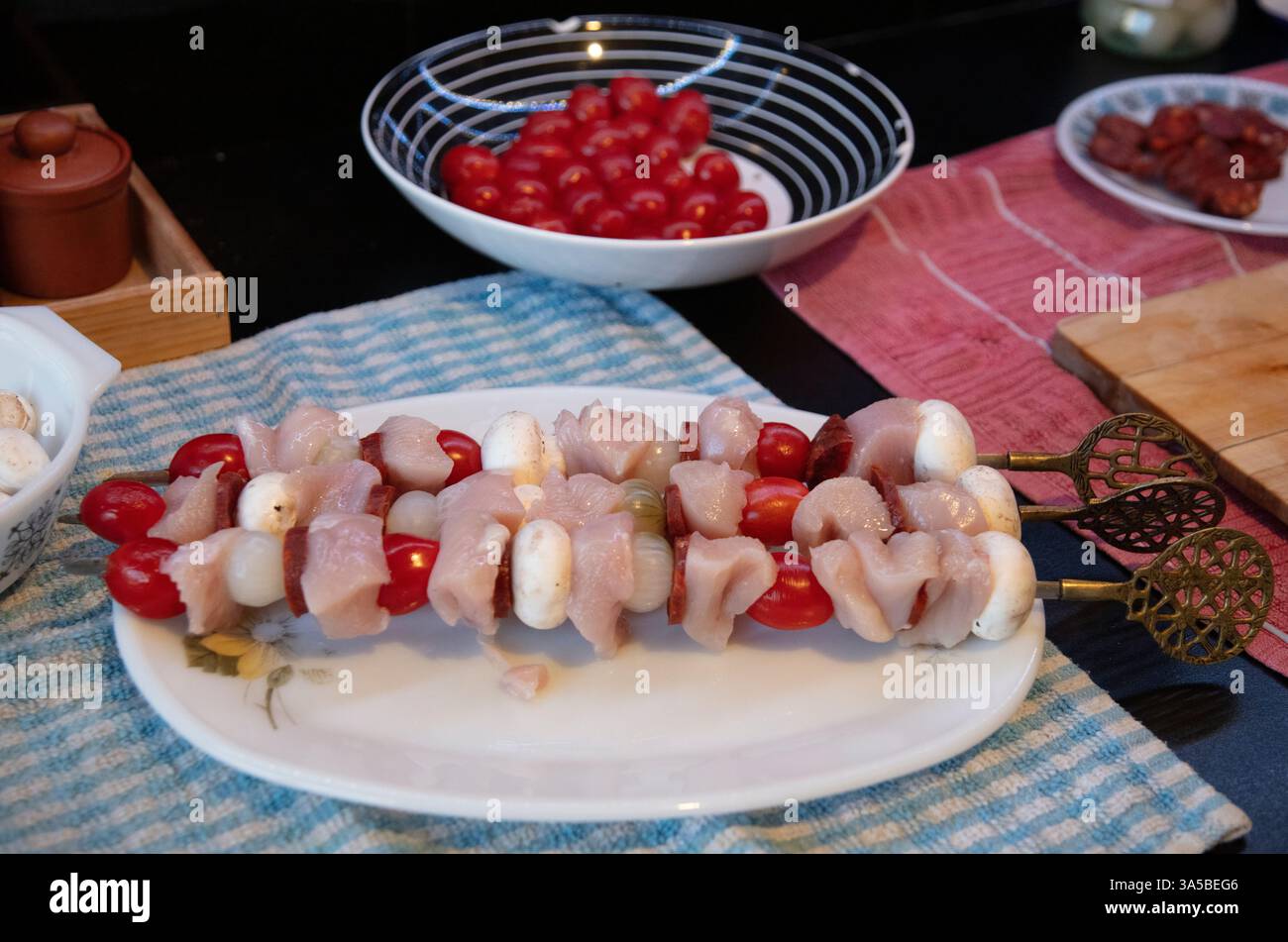 Un piatto bianco vintage con tre spiedini di pollo al kebab, pomodori ciliegini, cipolle e salsiccia Foto Stock