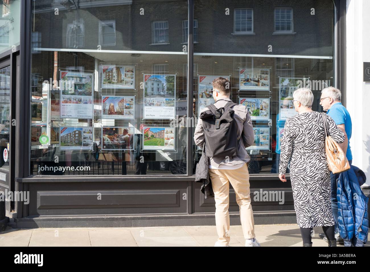 Pubblico in generale che guarda il poster delle proprietà in vendita sulle vetrine degli agenti immobiliari a Londra, Inghilterra, Regno Unito Foto Stock