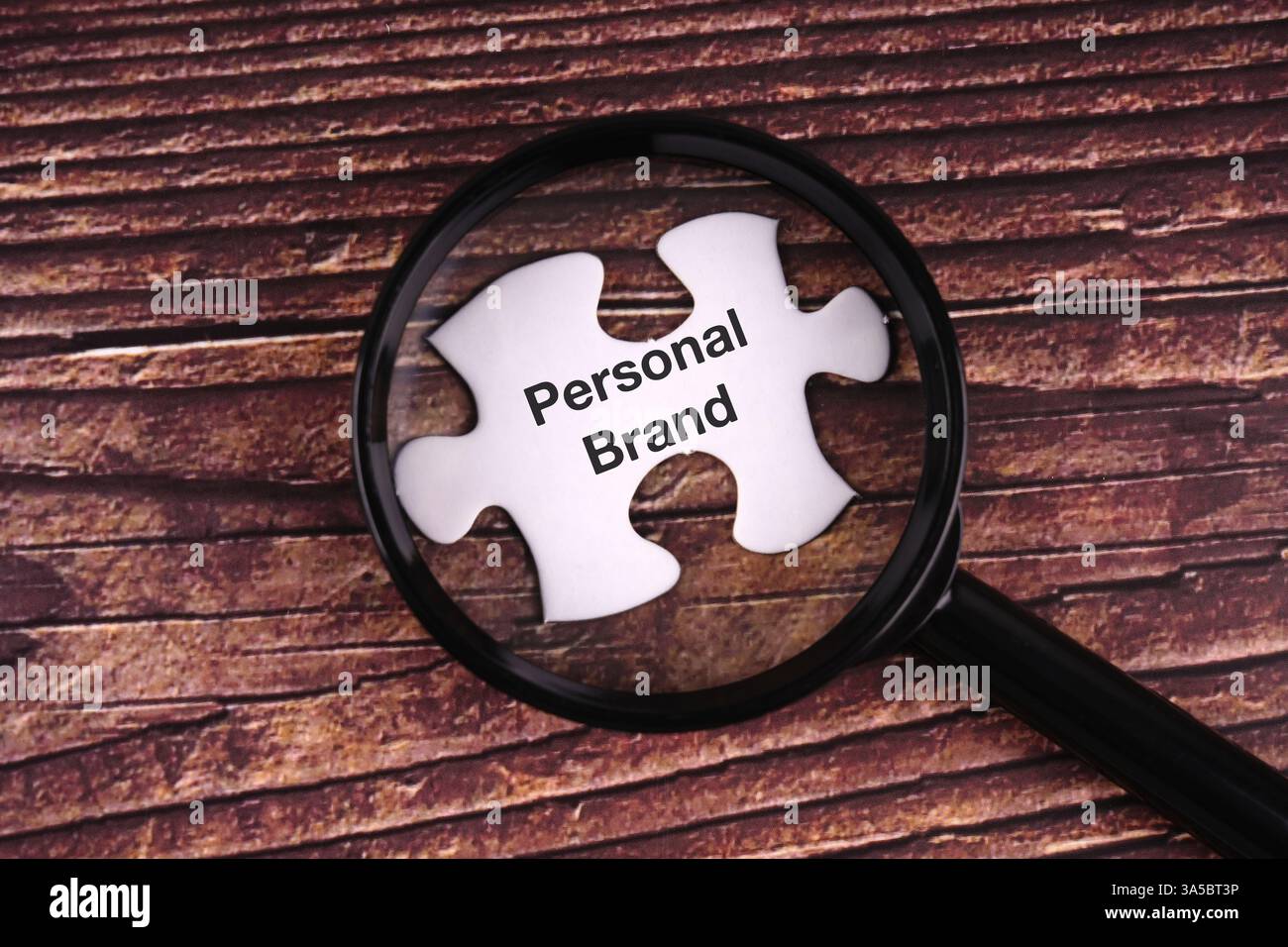 Lente d'ingrandimento incentrata sul testo personale del marchio sul puzzle Foto Stock