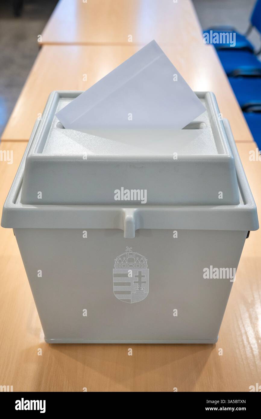 Urna con stemma ungherese e busta di voto su un tavolo Foto Stock
