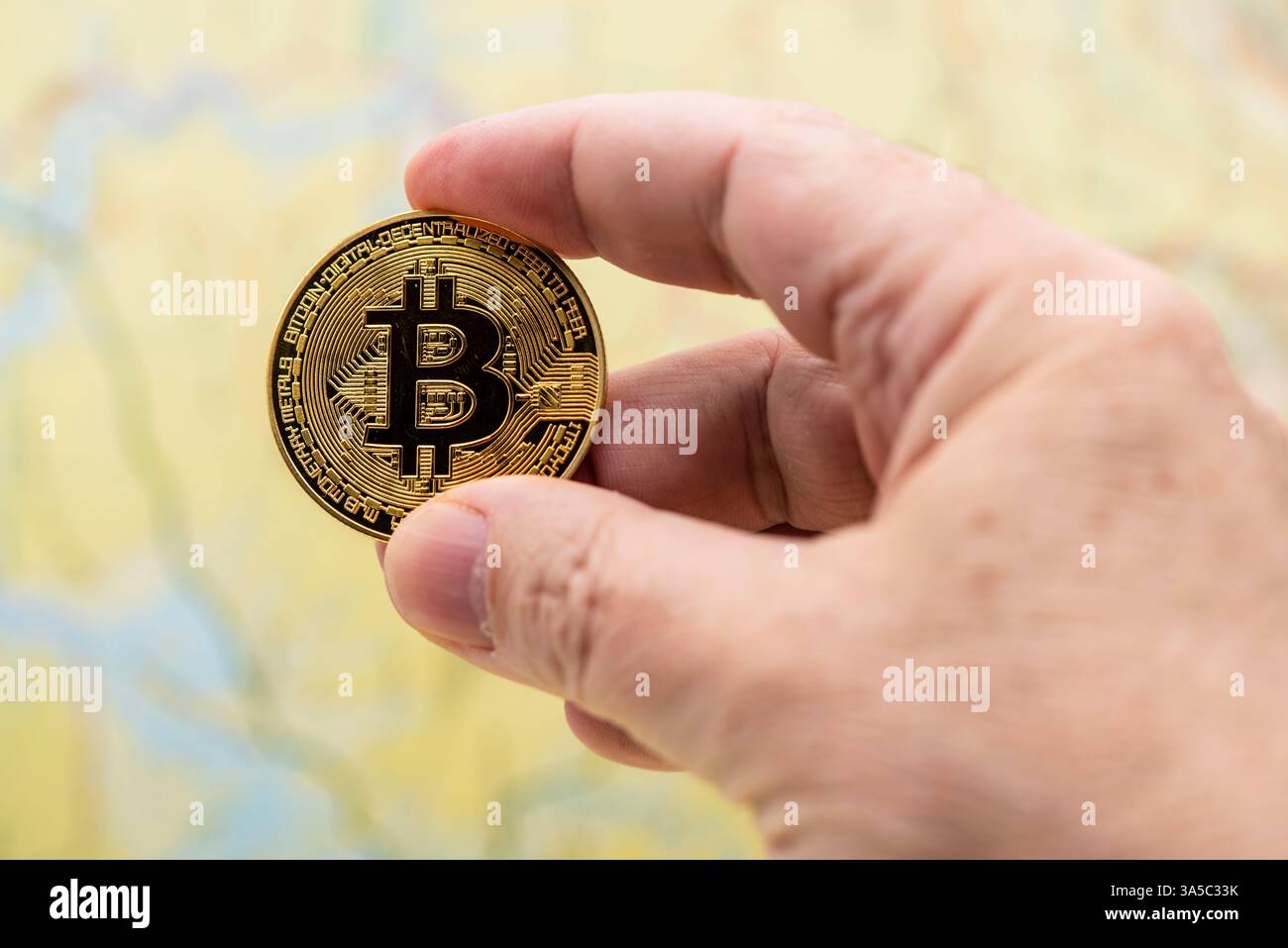 Dedos de una mano sujetando una criptomoneda de bitcoin Foto Stock