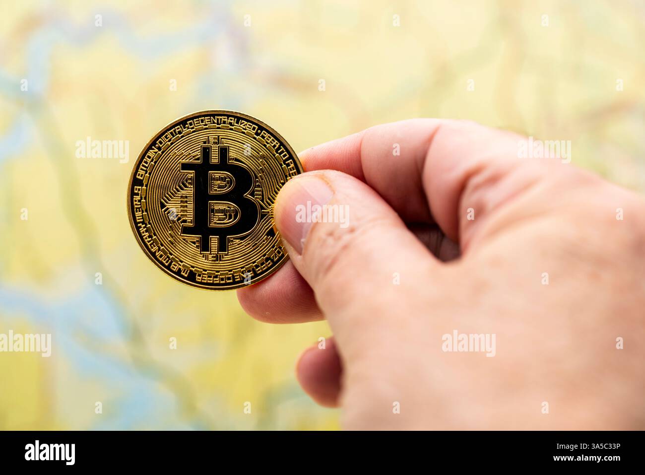 Dedos de una mano sujetando una criptomoneda de bitcoin Foto Stock