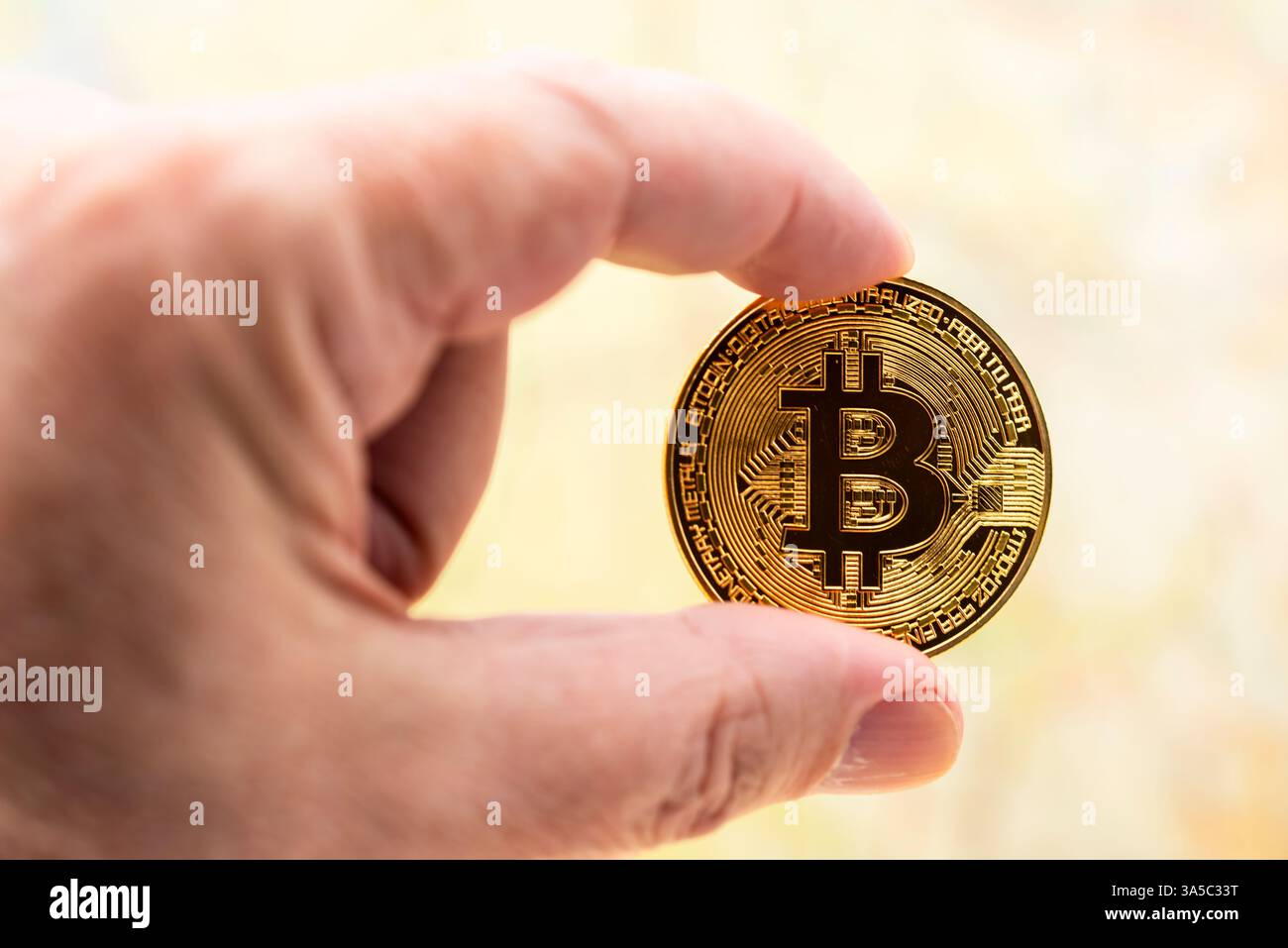 Dedos de una mano sujetando una criptomoneda de bitcoin Foto Stock
