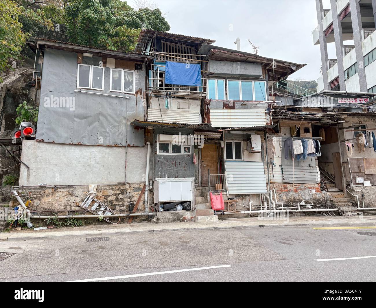 Fatiscenti capanne improvvisate a Chai Wan, Hong Kong, che mostrano alloggi informali e contrasto urbano. Foto Stock