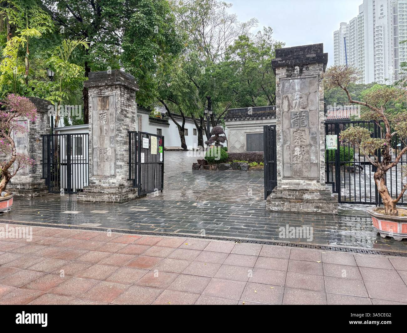Ingresso al Parco cittadino murato di Kowloon attraverso cancelli in pietra, che mostrano cancelli aperti, design tradizionale, vegetazione e disposizione del parco a Hong Kong. Foto Stock