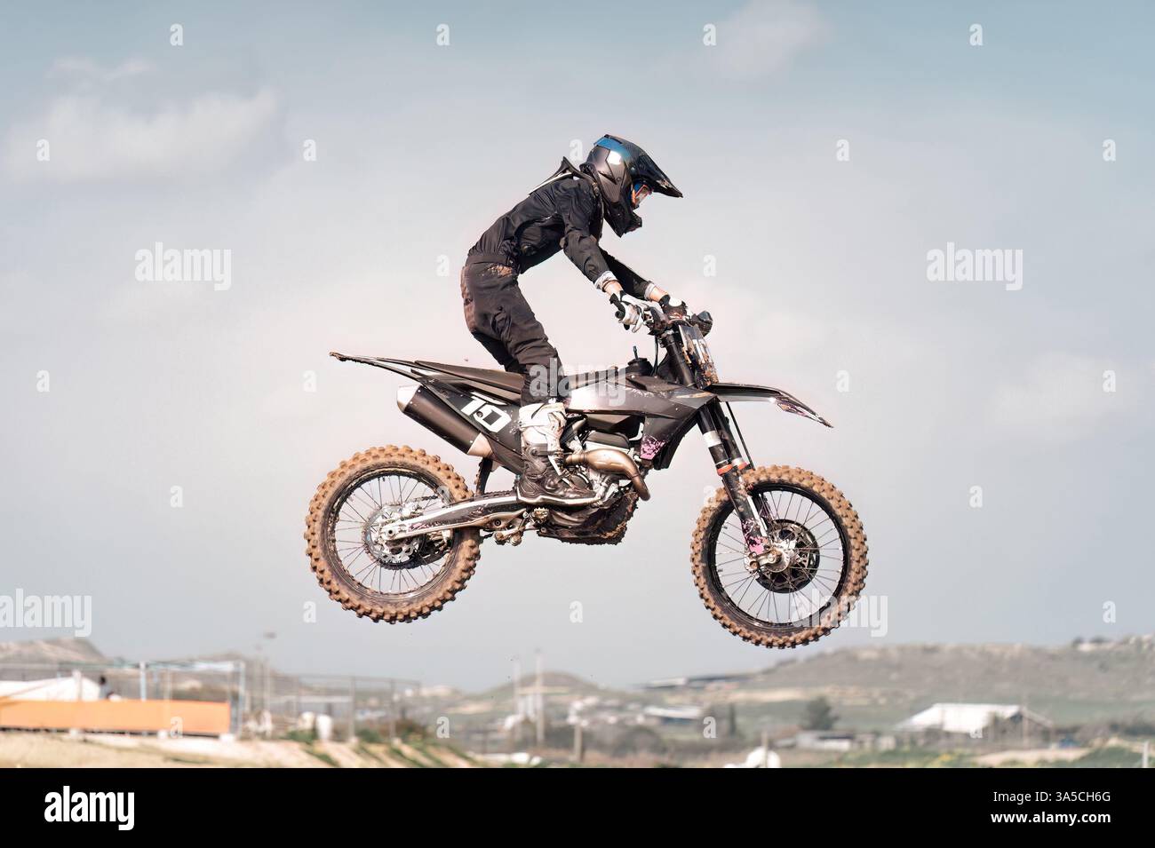 Il pilota di motocross sta volando in aria su una pista da motocross, dimostrando abilità e agilità Foto Stock