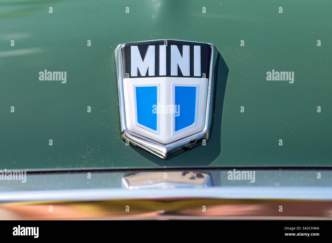 Larnaca, Cipro - 12 maggio 2024: Logo auto Mini vintage che risplende su un cappuccio verde metallizzato, che riflette l'iconico design automobilistico britannico e la sua tradizione Foto Stock