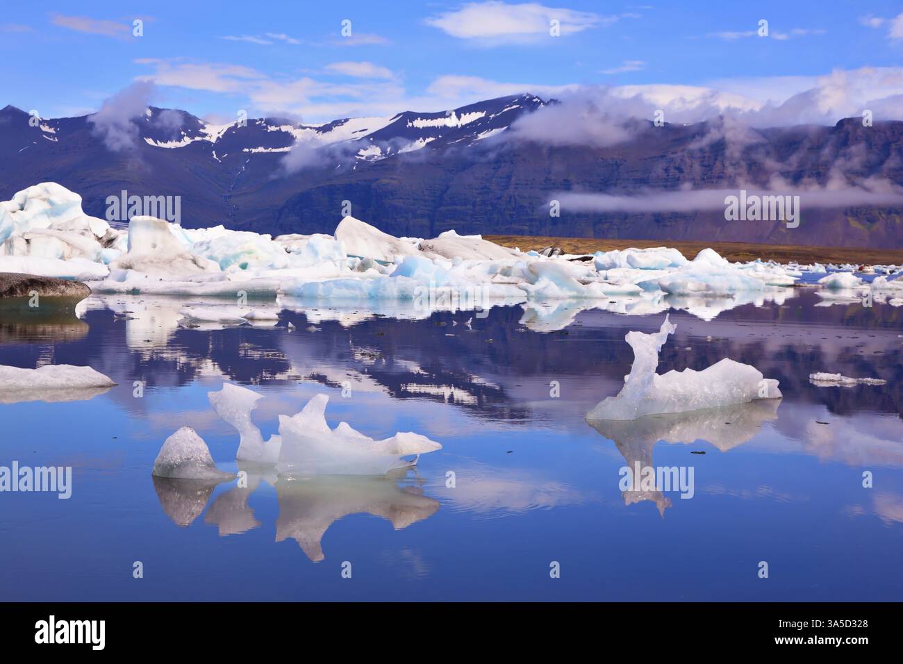 Iceberg e banchi di ghiaccio di forme freakish si riflettono in acqua liscia. Islanda a luglio. Laguna ghiacciata oceanica Joekulsarlon Foto Stock
