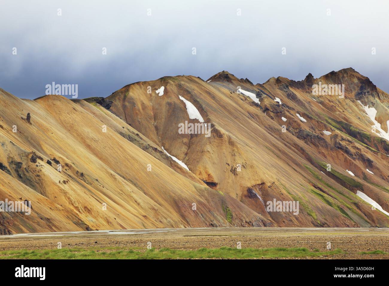 Dolci montagne di riolite arancioni nella riserva naturale di Landmannalaugar. Nelle cavità la neve rimasta dall'anno scorso Foto Stock