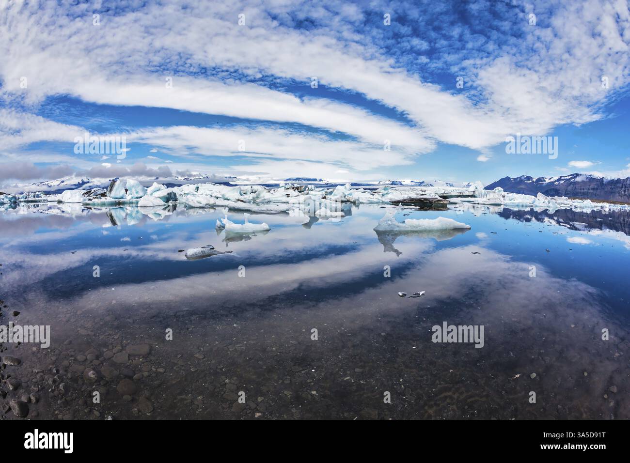 Laguna di ghiaccio in Islanda. Magnifica mattinata d'estate nel golfo dell'oceano con ghiacciai galleggianti. Le nuvole a strati che si espandono si riflettono in una navigazione fluida Foto Stock