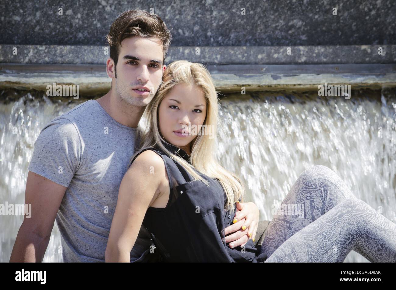 Fidanzato e fidanzata seduti di fronte a una grande fontana Foto Stock