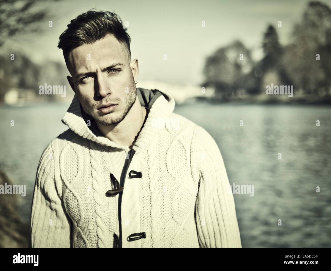 Un bel giovane in ambientazione urbana nella città europea, Torino in Italia, vicino al po, nelle fredde giornate invernali, che guarda la macchina fotografica Foto Stock