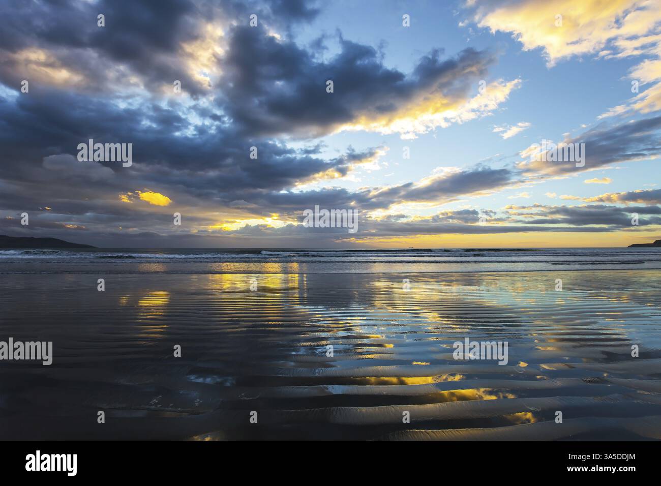 Calma mattutina. Il vento leggero provoca piccole increspature nell'acqua. I delicati colori delle nuvole si riflettono nell'acqua dell'oceano. Nuova Zelanda, costa del Pacifico. La conc Foto Stock