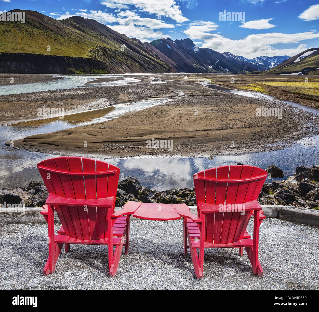 Montagne multicolore di riolite minerale sono illuminate dal sole. Due chaise longue rosse sono ideali per i turisti Foto Stock