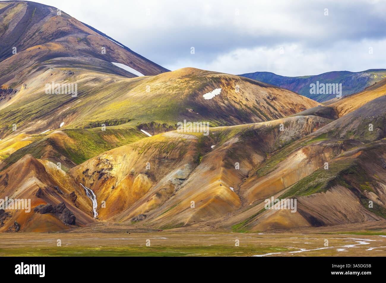 Le montagne multicolore di riolite minerale sono illuminate dal sole di luglio. Viaggio in Islanda in estate. Parco nazionale Landmannalaugar Foto Stock