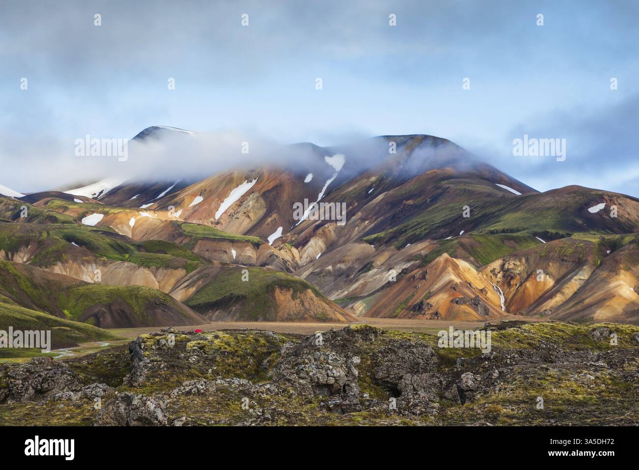 La neve si trova nelle cavità di montagne riolite multicolore. Mattina d'inizio estate nel Parco Nazionale di Landmannalaugar, Islanda, Europa Foto Stock