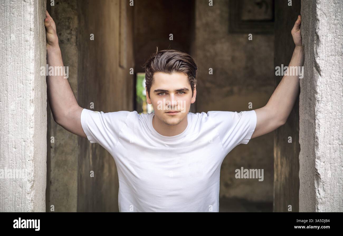 Giovane uomo con i bracci aperti sulla soglia, con sguardo fiducioso Foto Stock