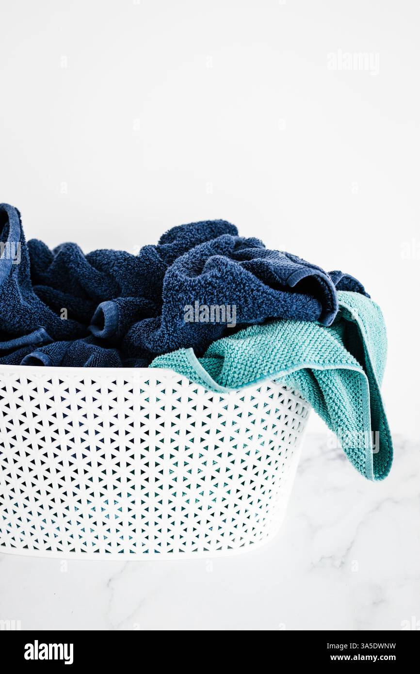 cestino per la lavanderia pieno di asciugamani da bagno, blu e tè, su sfondo minimalista in marmo bianco, concetto di articoli per la casa e per il giorno Foto Stock cestino per la lavanderia pieno di asciugamani da bagno, blu e tè, su sfondo minimalista in marmo bianco, concetto di articoli per la casa e per il giorno Foto Stock