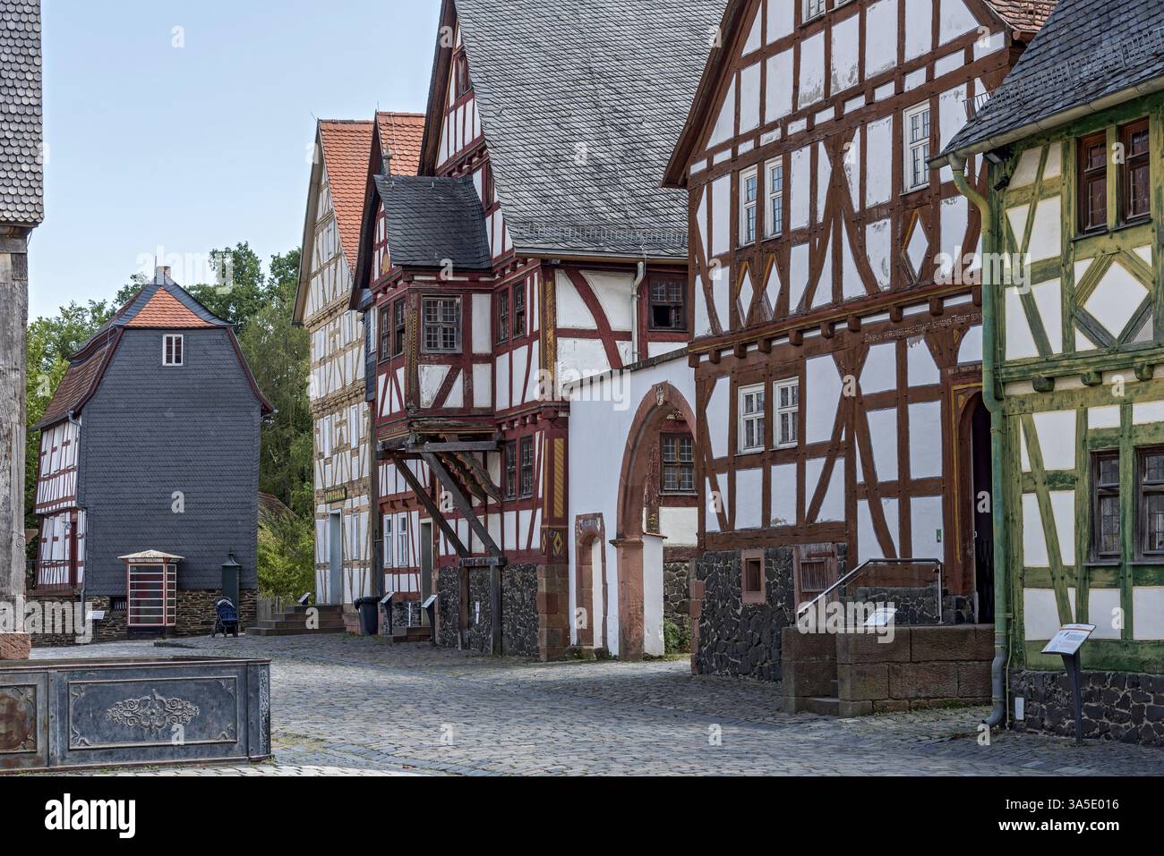 Strada con storiche case in legno, sul retro una casa di Idstein ricoperta di tegole di ardesia, Hessenpark Open-Air Museum, Neu-Anspach, Taunus Foto Stock