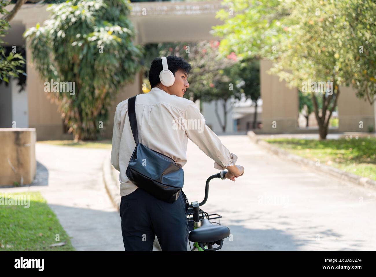 Escursioni in bicicletta e esplorazione urbana. Un giovane cavalca la sua bicicletta, ascoltando musica in un ambiente all'aperto. Foto Stock