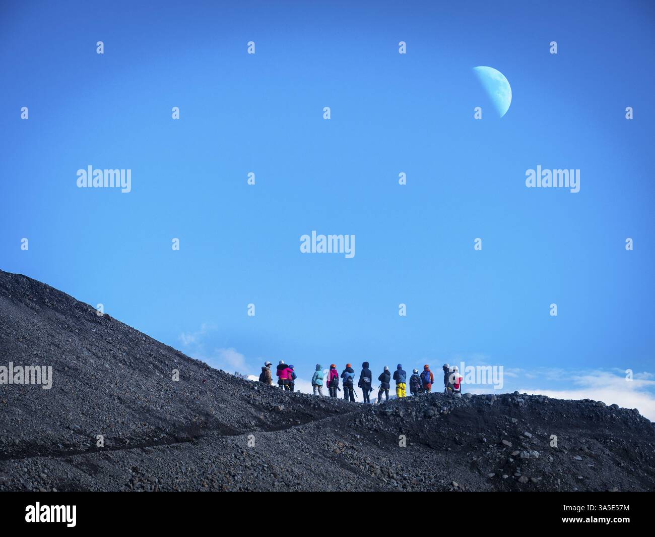 Vista posteriore di alpinisti professionisti in vestiti caldi camminando sulla superficie ghiacciata glacier dalla montagna innevata in Islanda Foto Stock