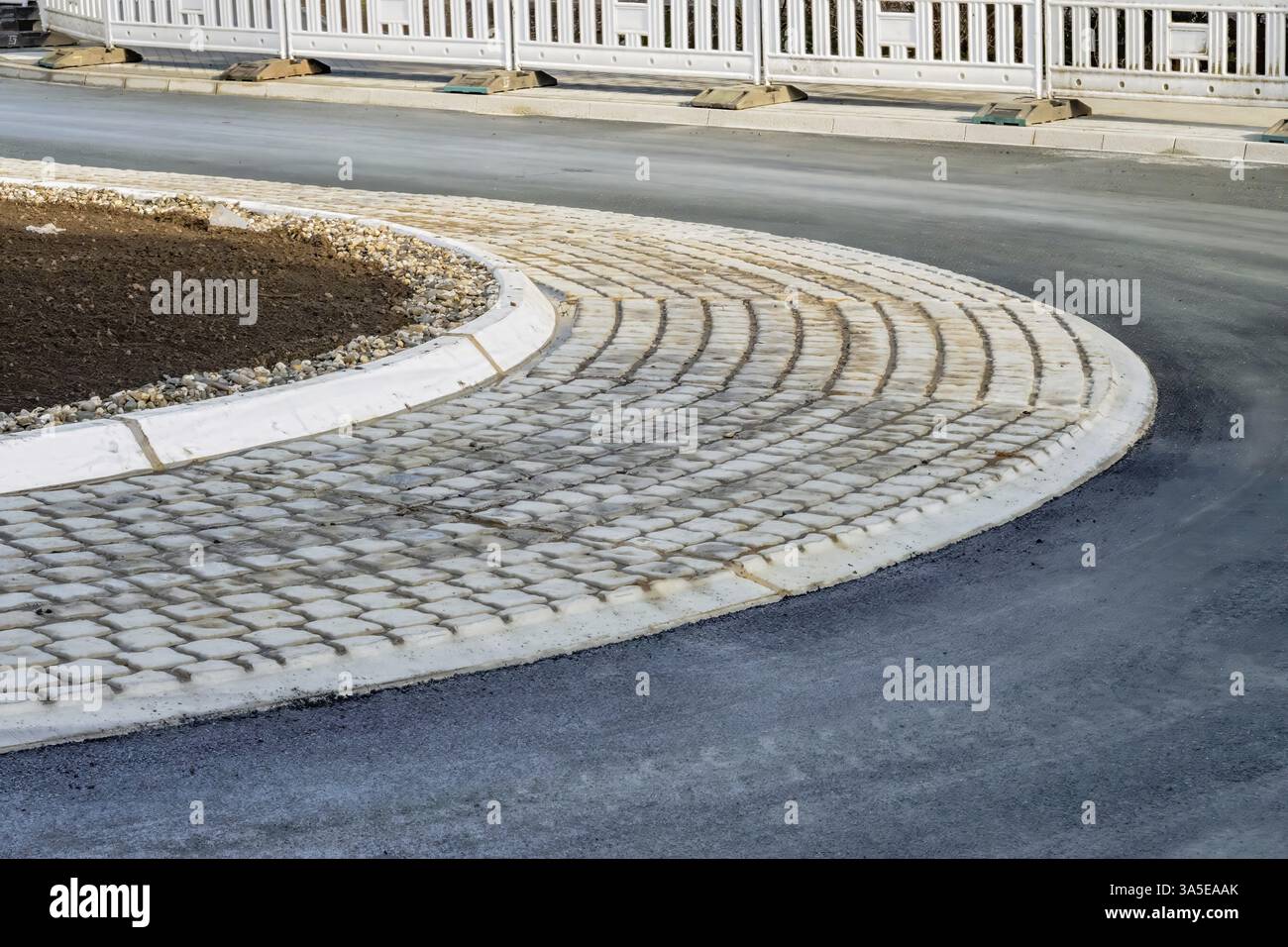 Nuovo marciapiede in ciottoli che separa una strada asfaltata da un lotto vuoto, vicino a una recinzione temporanea, Bottrop, NRW, Germania, Europa Foto Stock