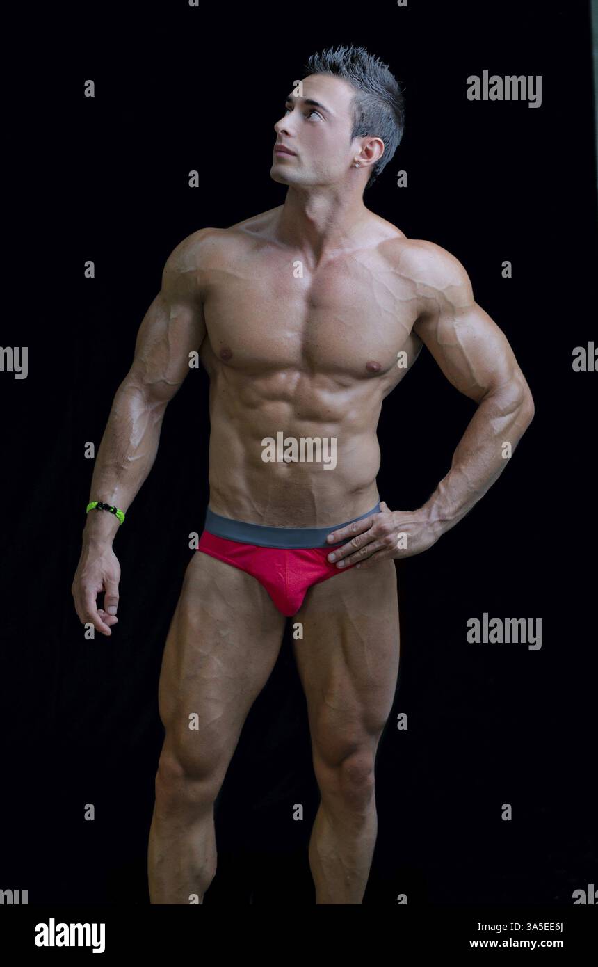 Giovane culturista muscoloso in posa rilassata, che guarda su un lato. Isolato sul nero Foto Stock
