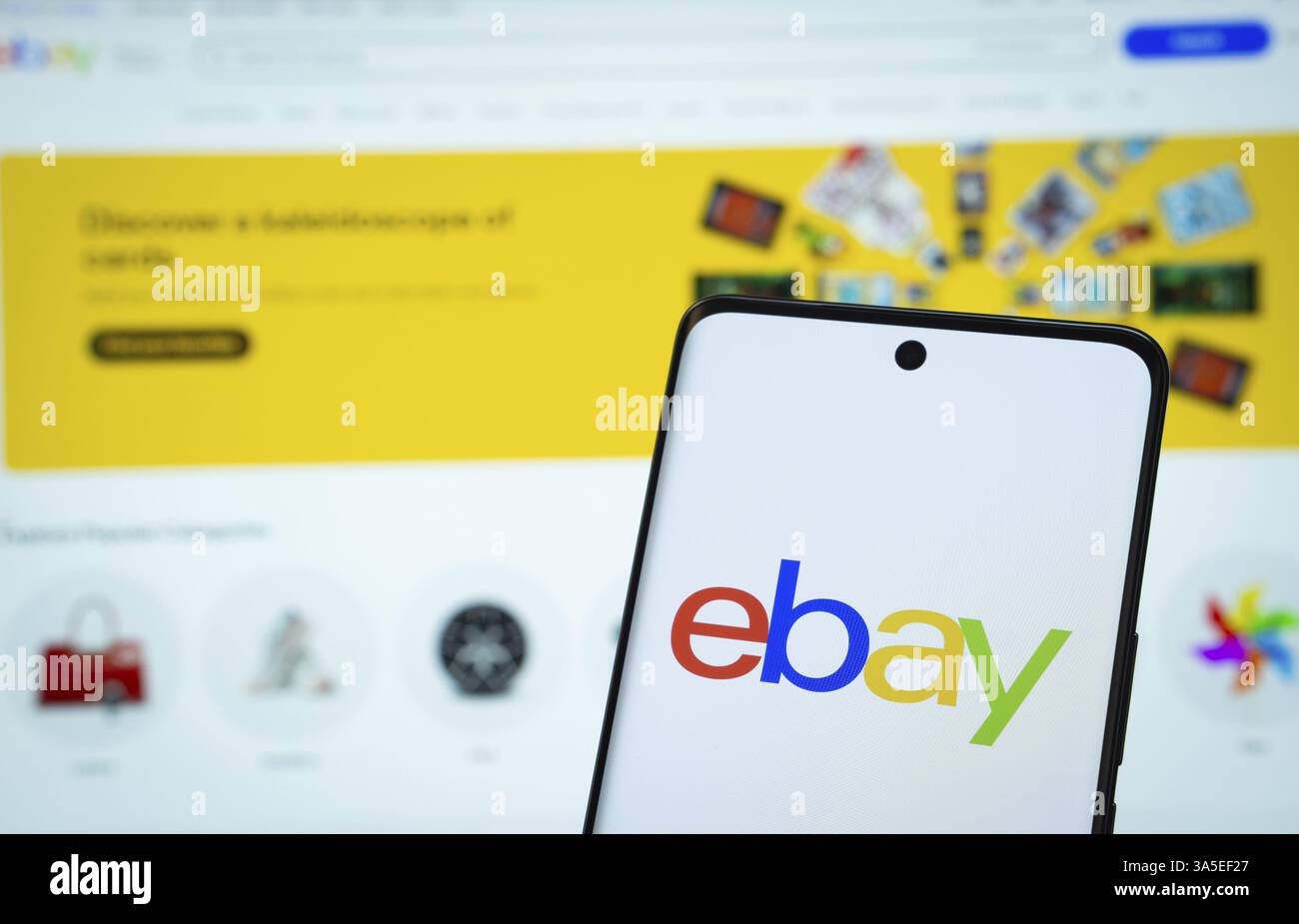 Il logo di ebay viene visualizzato sullo schermo di uno smartphone e il sito Web ebay è visibile sullo schermo di un computer sullo sfondo Foto Stock