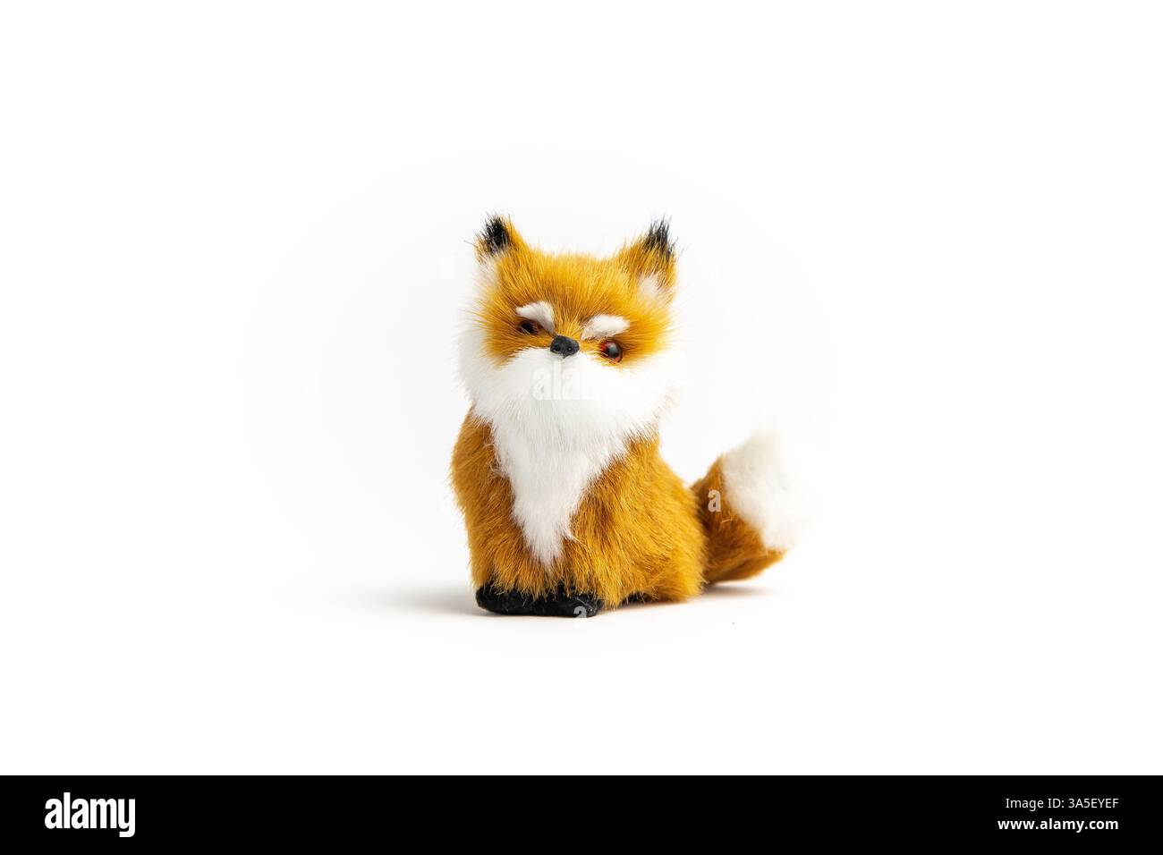 Un piccolo peluche volpe si trova su uno sfondo bianco. Ha una pelliccia arancione e bianca e un naso nero. Foto Stock