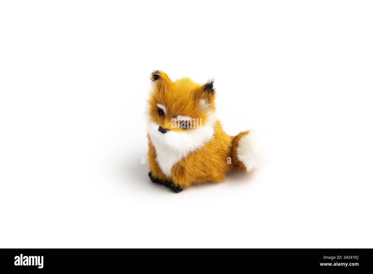 Un piccolo peluche volpe si trova su uno sfondo bianco. Ha una pelliccia arancione e bianca e un naso nero. Foto Stock