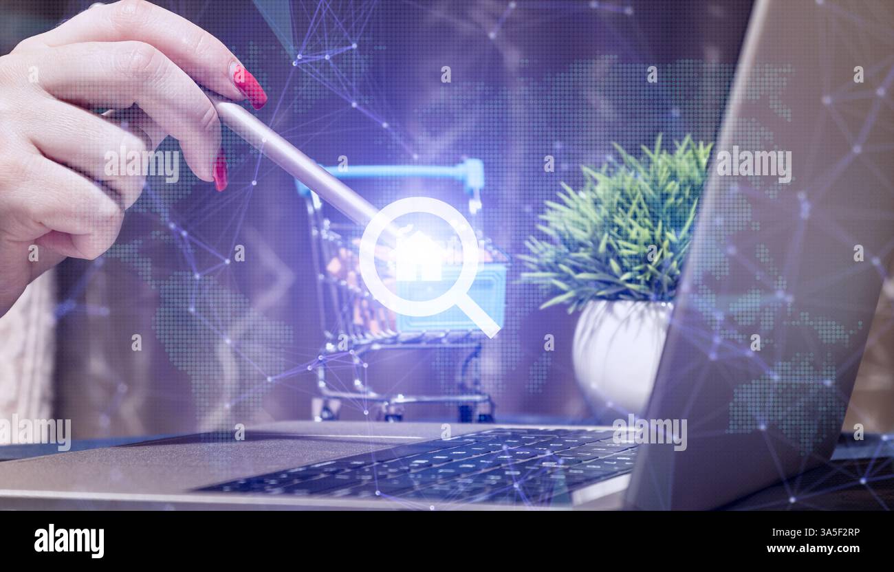 Ricerca immobiliare digitale e spazio di lavoro per l'e-Commerce con la mano utilizzando lo stilo sull'icona del carrello, laptop con grafica di rete, Green Plant e Moder Foto Stock