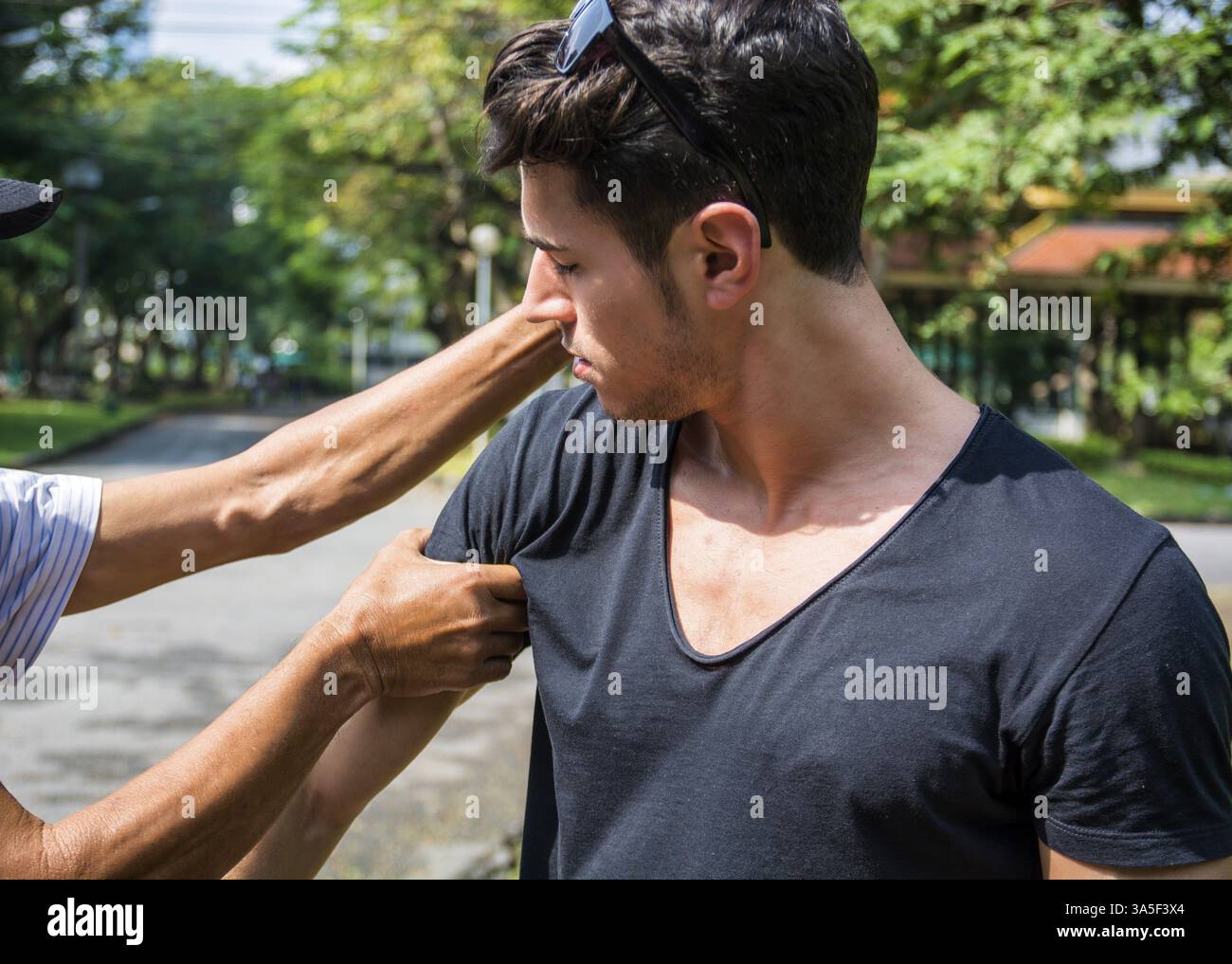 Giovane uomo in piedi e che riceve un massaggio alle mani. Ripresa orizzontale all'aperto Foto Stock