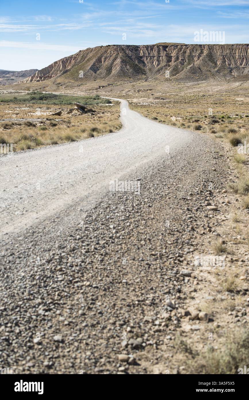La selvaggia strada occidentale sterrata verso l'orizzonte. Visione cinematografica americana. Strada nel deserto e montagna rocciosa sullo sfondo. Concetto di viaggio e film Foto Stock