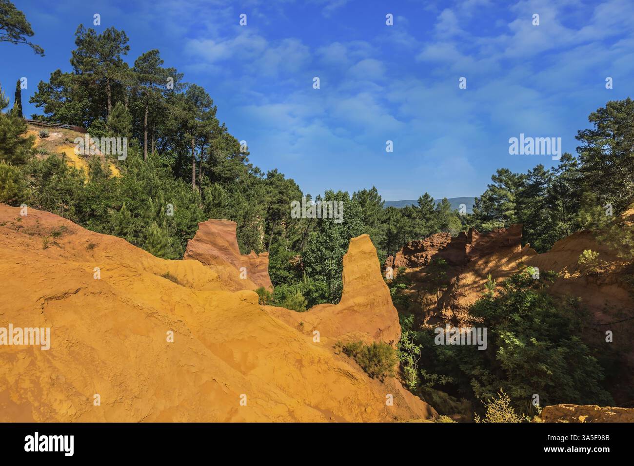 Roussillon, il Villaggio Rosso della Provenza. Affioramenti ocra multicolore - dal giallo all'arancio-rosso. Gli alberi verdi creano un bel contrasto con l'ocra Foto Stock