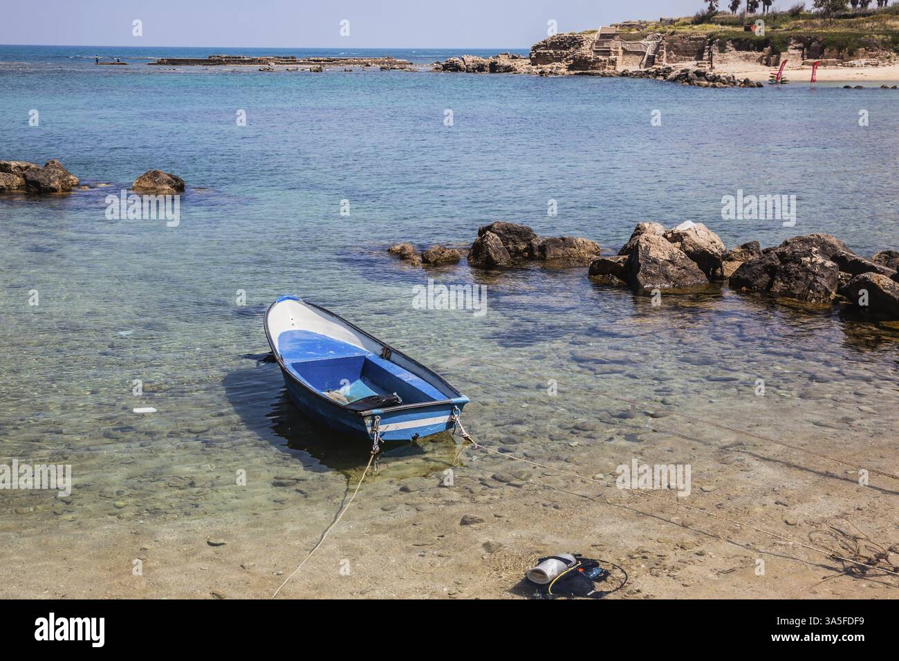 La baia poco profonda e la barca da pesca blu, ormeggiata vicino alla riva. Accanto alla barca - equipaggiamento per immersioni Foto Stock