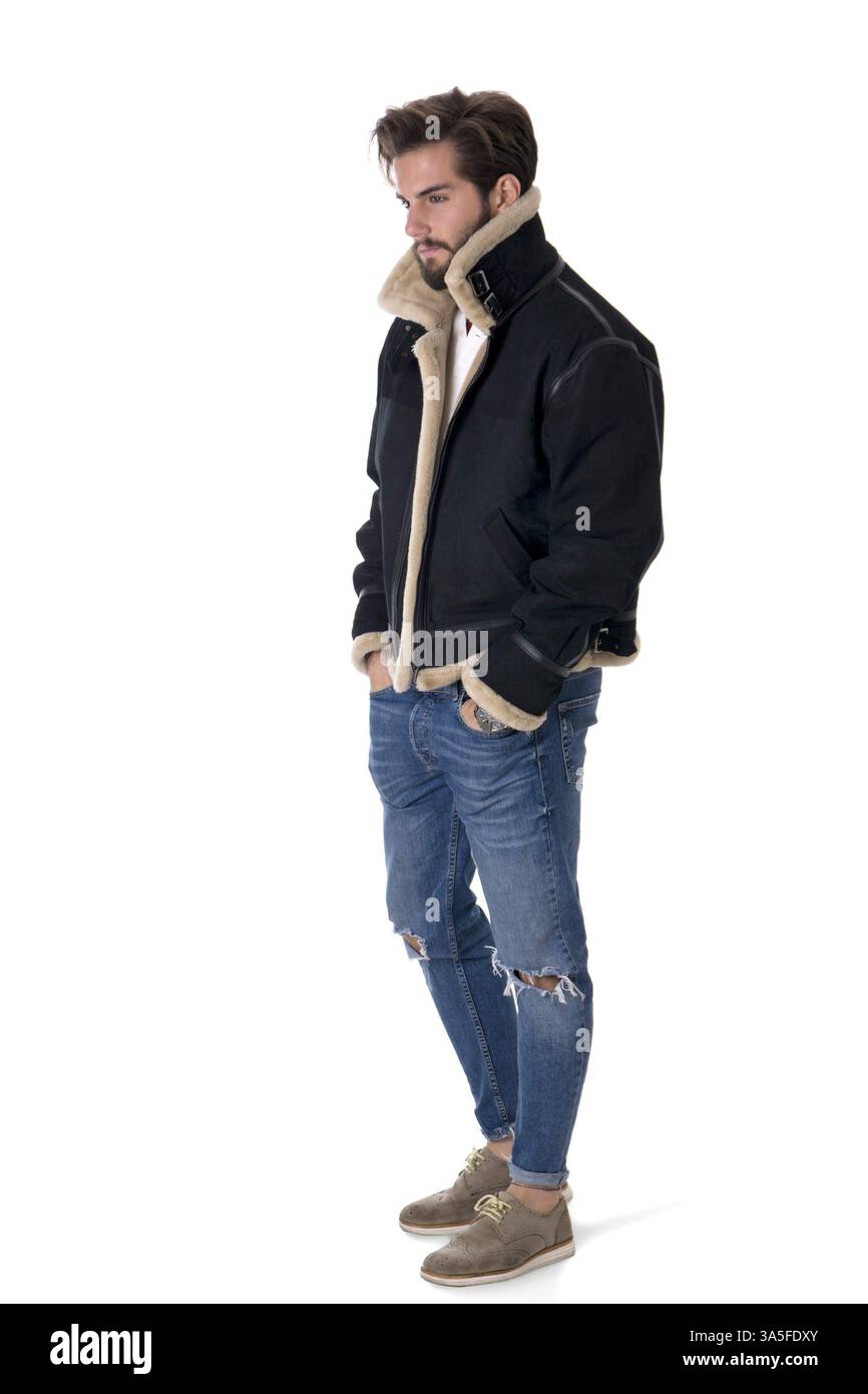 Giovane uomo moderno in denim e giacca calda con le mani in tasca isolata su sfondo bianco in studio Foto Stock