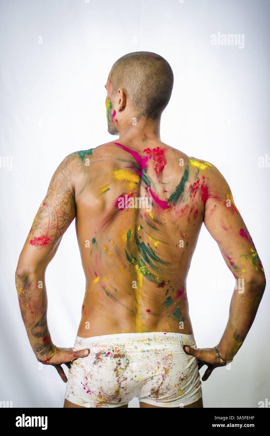Bel giovane uomo visto dal retro con la pelle tutte dipinte con colori Holi Foto Stock