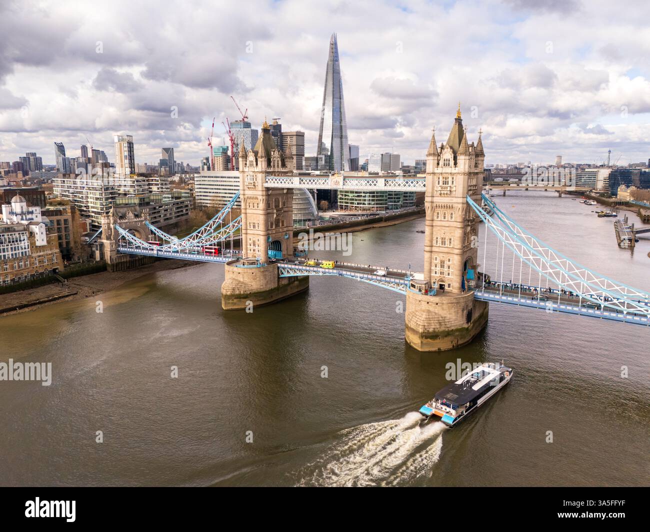 Vista aerea del Tower Bridge sul Tamigi a Londra con una nave turistica per passeggeri che passa sotto, mostrando The Shard sullo sfondo Foto Stock