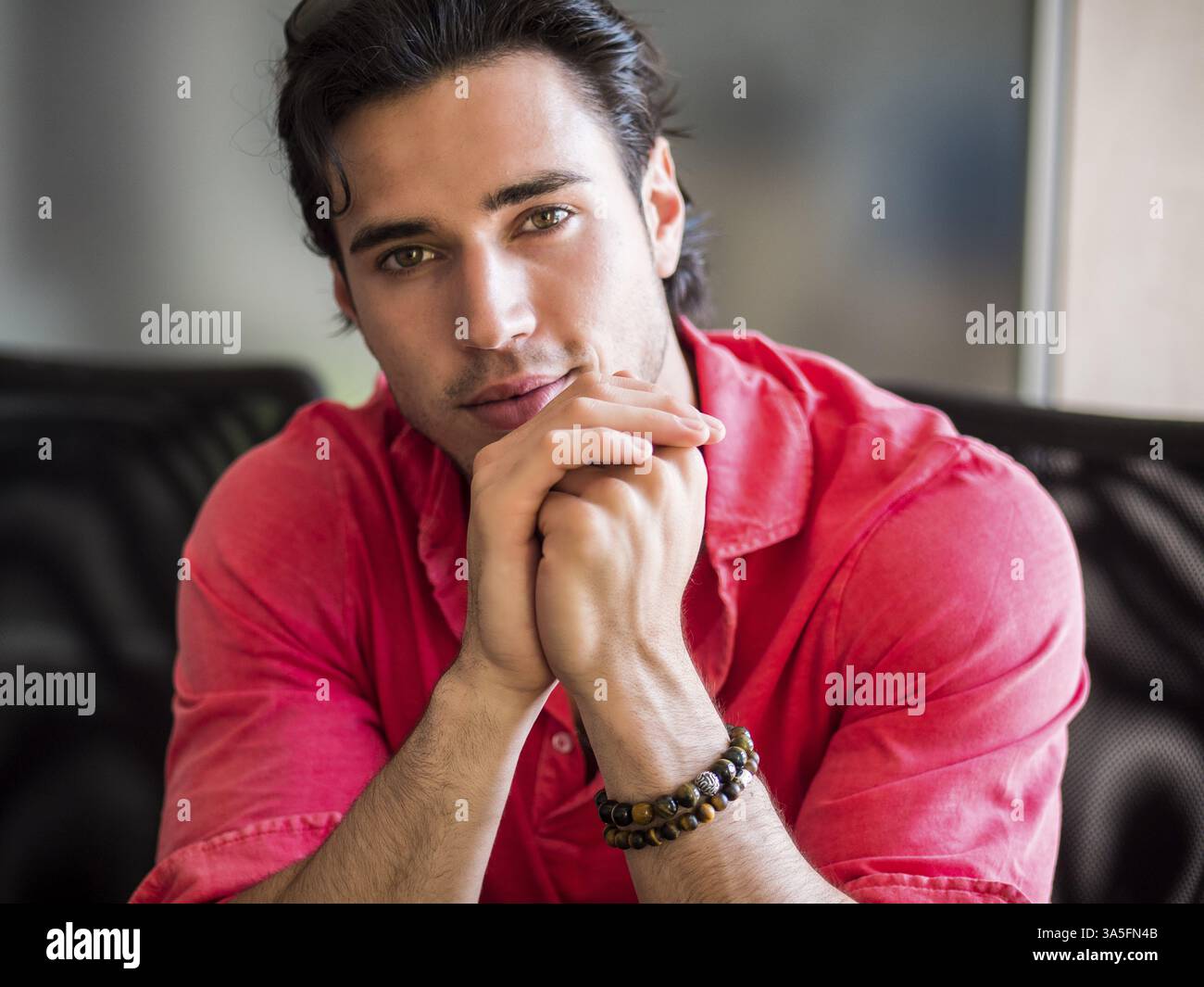 Giovane uomo attraente in interni con camicia e braccialetti con perline Foto Stock