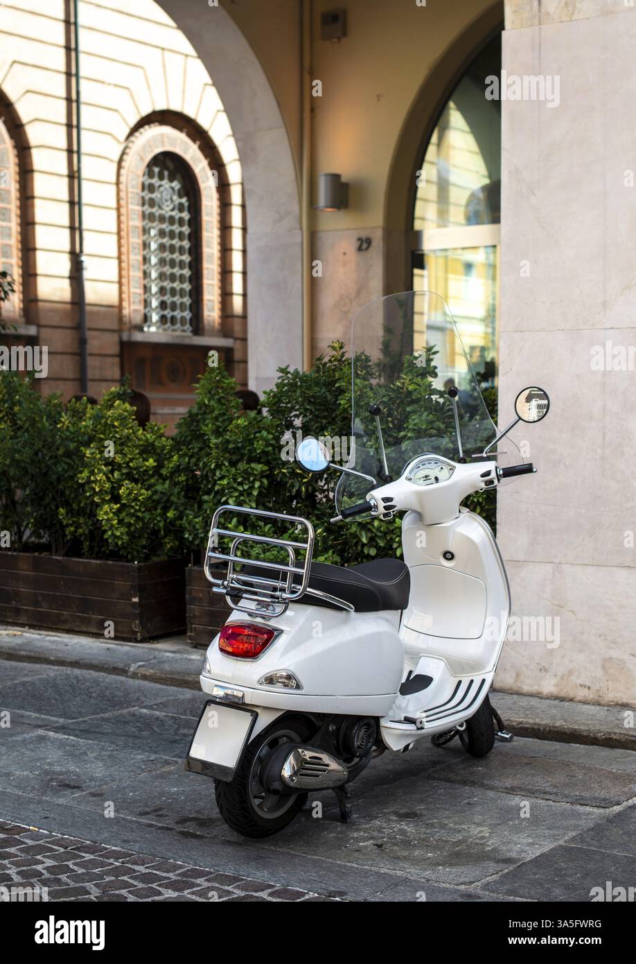 Scooter italiano bianco su strada italiana. Tipica architettura italiana sullo sfondo. Tipico stile motociclistico italiano Foto Stock