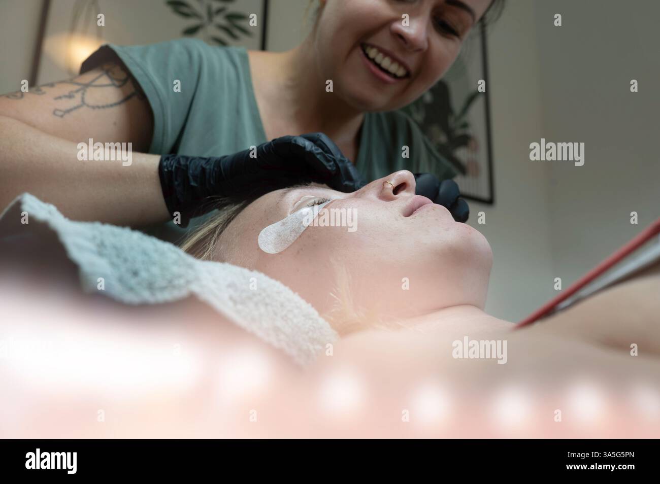 Primo piano di bellezza di una giovane donna che si solleva la ciglia con un sollevamento ciglia da parte di un estetista in un salone di bellezza. Dare forma alle sopracciglia. Foto Stock