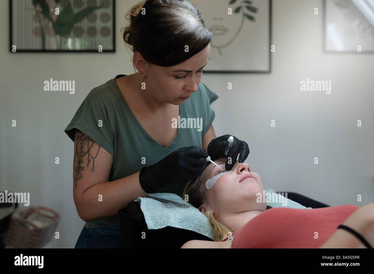 Primo piano di bellezza di una giovane donna che si solleva la ciglia con un sollevamento ciglia da parte di un estetista in un salone di bellezza. Dare forma alle sopracciglia. Foto Stock