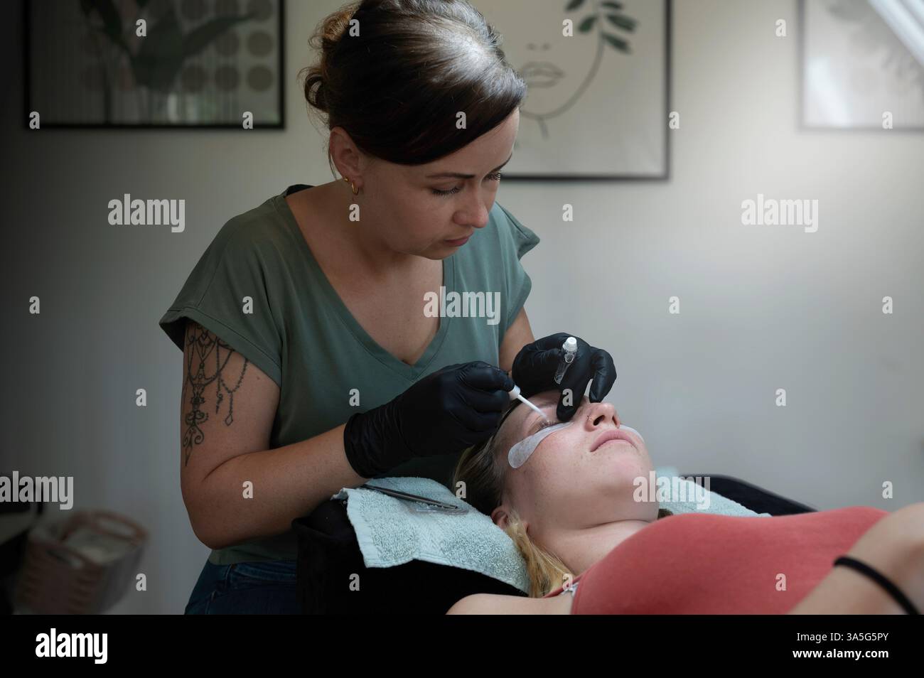 Primo piano di bellezza di una giovane donna che si solleva la ciglia con un sollevamento ciglia da parte di un estetista in un salone di bellezza. Dare forma alle sopracciglia. Foto Stock